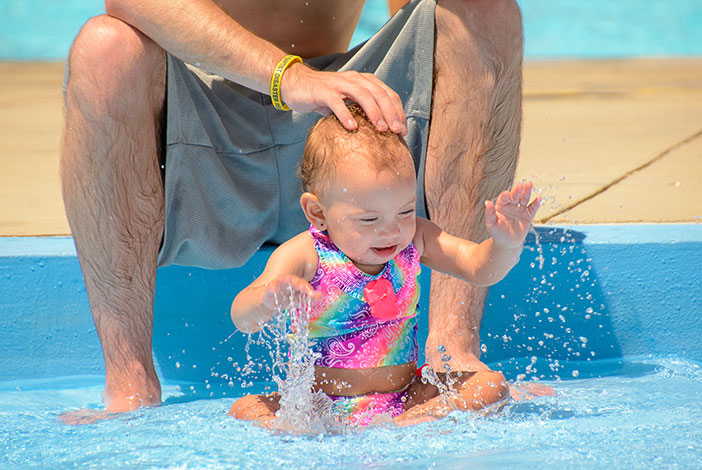 Photo: Baby splashes in pool while being watched by Dad.