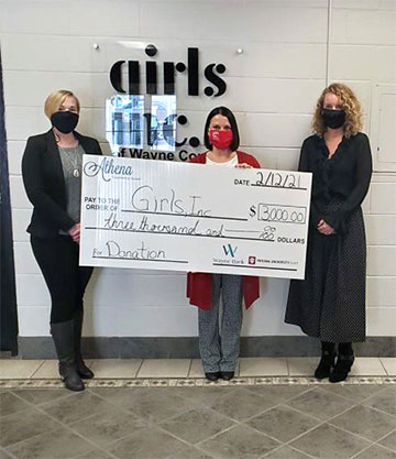 Supplied Photo: 3 women with oversize check in front of Girls, Inc. sign.