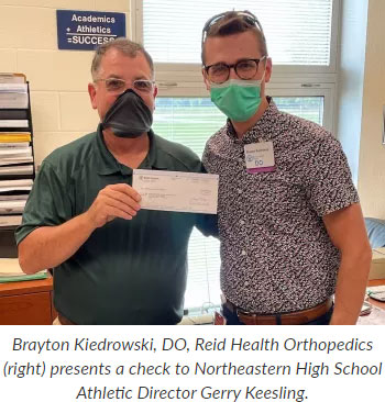 Supplied Photo: Brayton Kiedrowski, DO, Reid Health Orthopedics (right) presents a check to Northeastern High School Athletic Director Gerry Keesling.