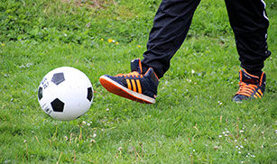 Stock Photo: Child's foot kicking soccer ball.
