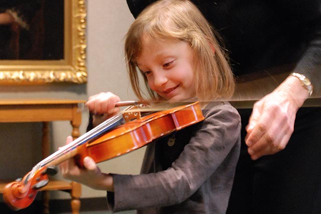 Photo: Young girl experiences playing the violin for the first time.